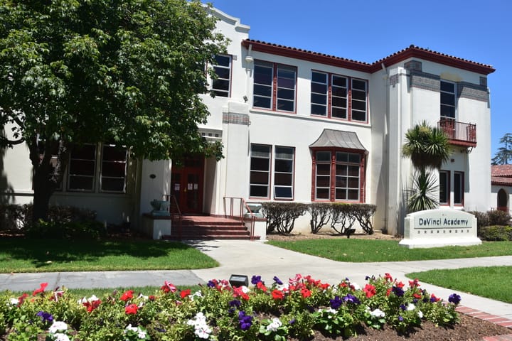 Two-story building with terra cotta tiles, front steps and a sign stating, "DaVinci Academy".