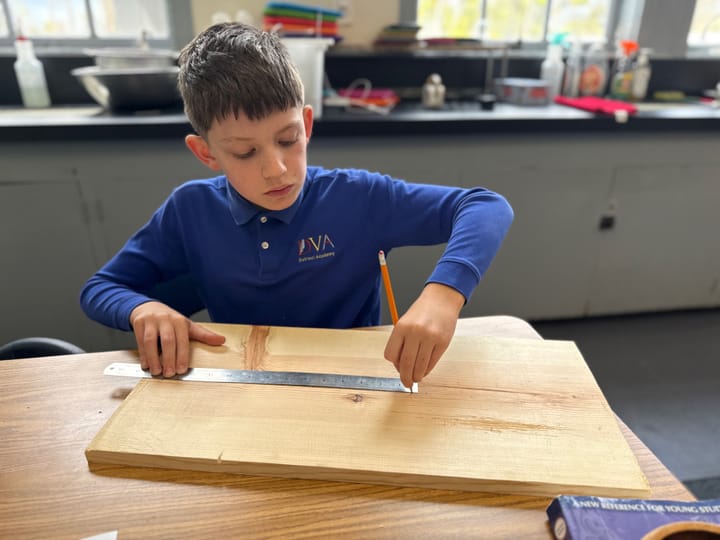 Male fourth grade student using ruler on wood for STEM project